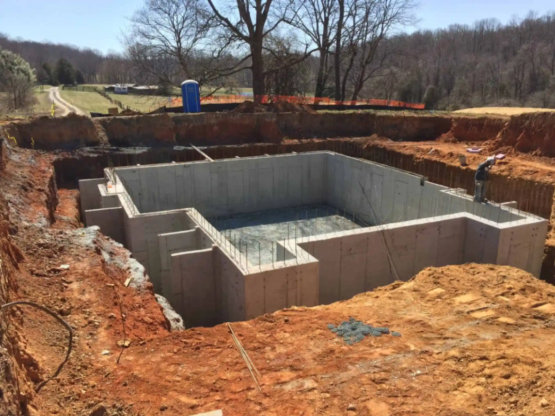 Newly poured concrete foundation walls at a residential construction site.