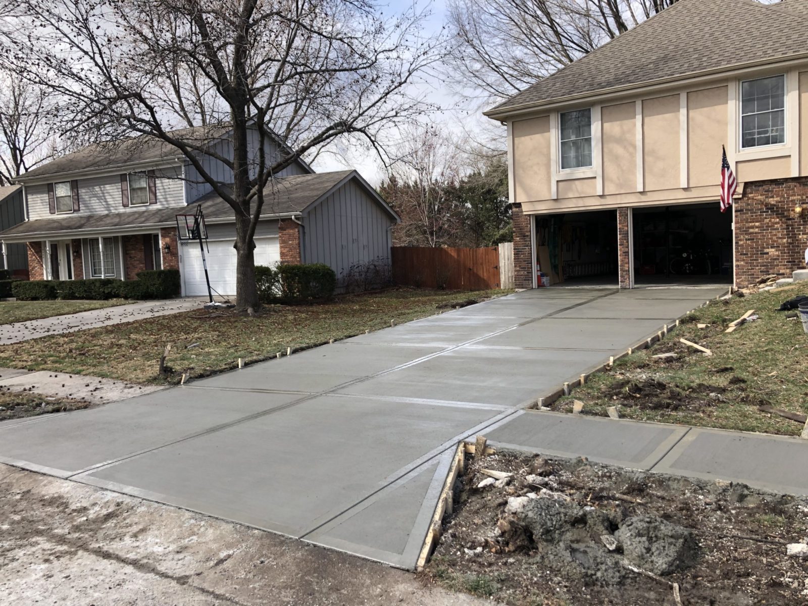 Freshly poured concrete driveway with clean control joints leading to a residential garage.