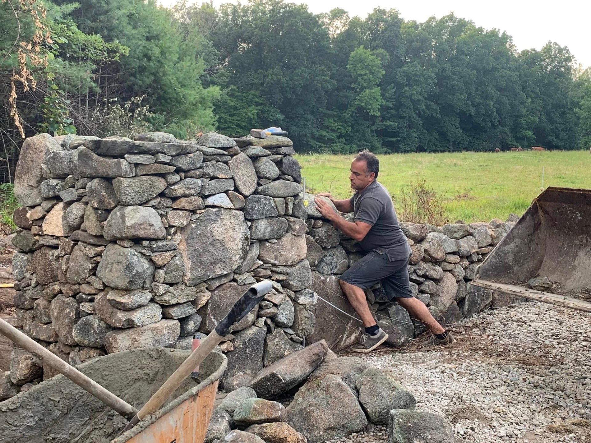 Andre building a stone retaining wall on a residential property.