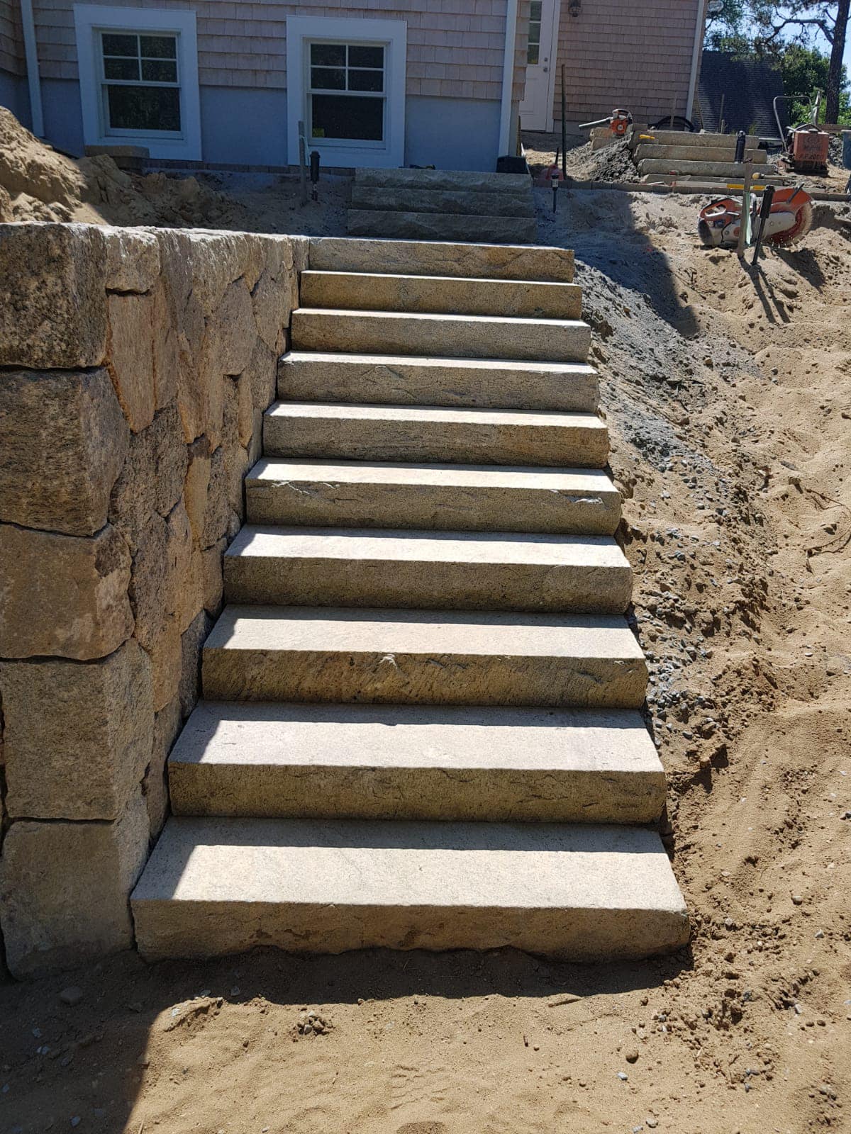 Concrete stairway with stone retaining wall at a residential property.